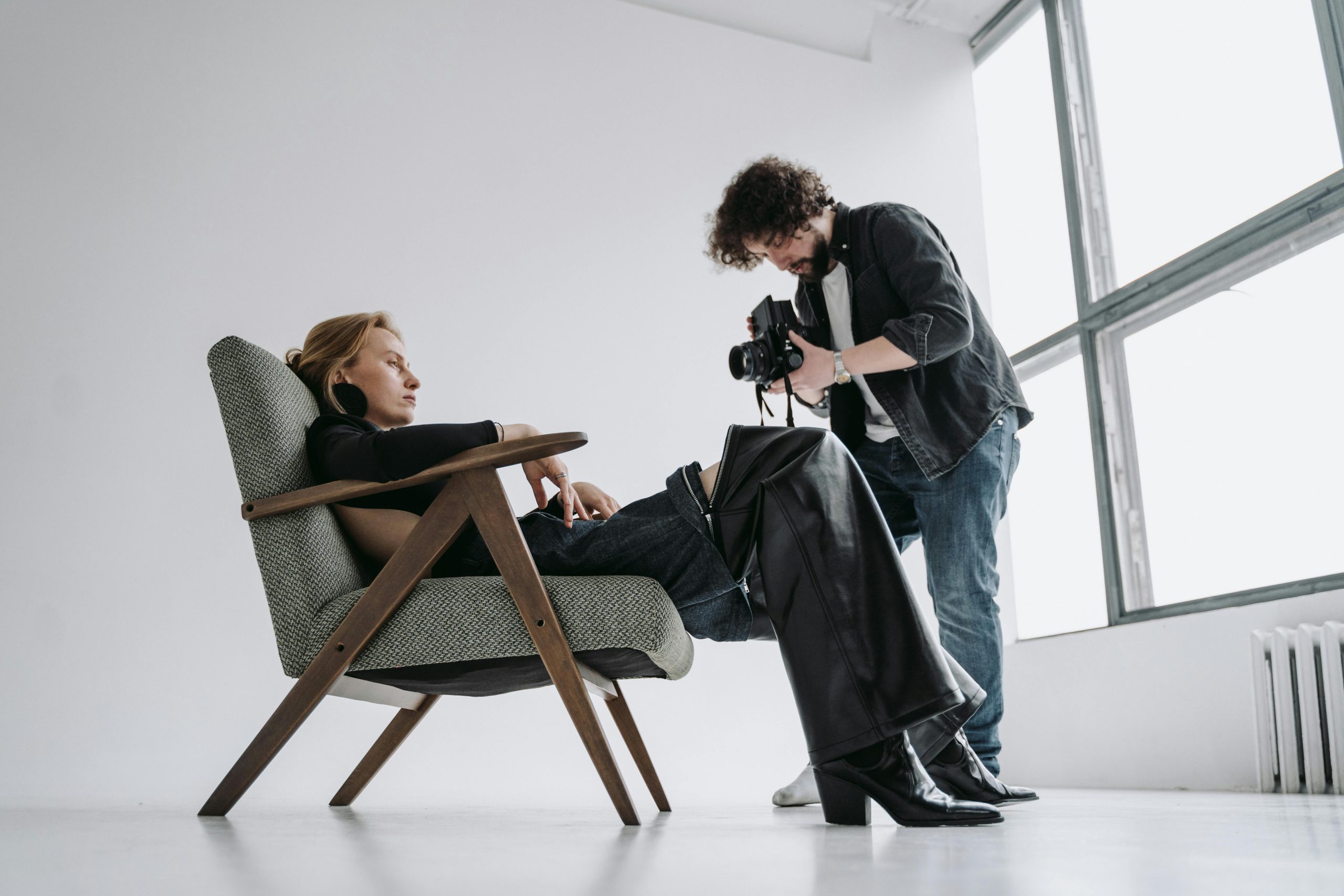 A photographer captures a reclining model in a modern studio setting, showcasing fashion and artistry.